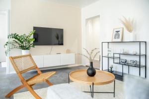 uma sala de estar com uma televisão, uma cadeira e uma mesa em Stilvolles Apartment in Bayreuther Fußgängerzone em Bayreuth