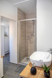 La salle de bains est pourvue d'une douche et d'un lavabo blanc. dans l'établissement Stilvolles Apartment in Bayreuther Fußgängerzone, à Bayreuth