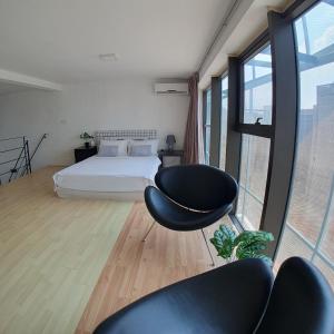 1 dormitorio con 1 cama, 2 sillas y ventanas en My Houze - Empire Damansara Duplex en Kampong Bukit Lanjan