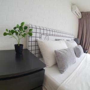 Una cama con almohadas blancas y una mesa con una planta. en My Houze - Empire Damansara Duplex en Kampong Bukit Lanjan