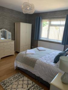 a bedroom with a bed and a dresser and windows at Hafan Traeth in Prestatyn