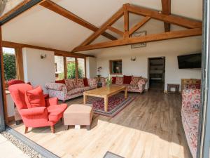 a living room with red chairs and a table at The Old Farmhouse in Craven Arms