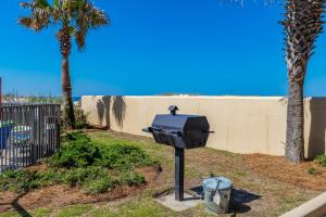 a barbecue grill in a yard with palm trees at Phoenix All Suites West Hotel in Gulf Shores