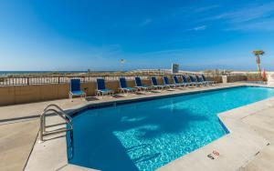 una piscina con sillas y el océano en el fondo en Phoenix All Suites West Hotel en Gulf Shores