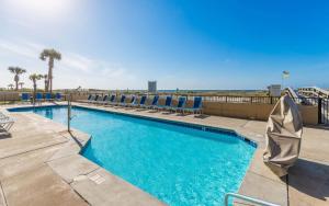 a swimming pool with lounge chairs and the ocean in the background at Phoenix All Suites West Hotel in Gulf Shores