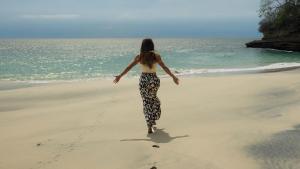 Una mujer caminando por la playa cerca del océano en Hostel-Island Paradise, Saboga Lodge and Villa Noelia, en Panamá