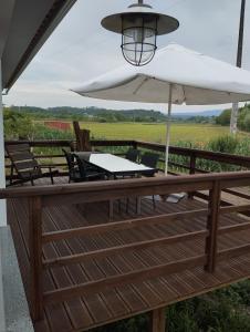a table with a white umbrella on a wooden deck at CASINHA DO RIO in Soure