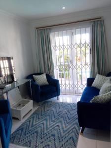 a living room with blue furniture and a large window at Blue Waves Lodge in Durban