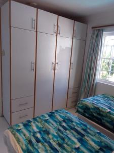 a bedroom with two beds and cabinets and a window at Blue Waves Lodge in Durban