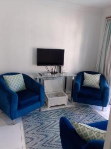 a living room with two blue chairs and a tv at Blue Waves Lodge in Durban