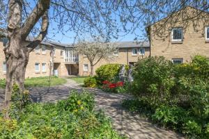 a building with a tree and flowers in front of it at Comfy Central Apartment in Cambridge in Cambridge