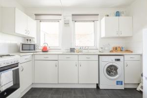 a kitchen with white cabinets and a washer and dryer at Comfy Central Apartment in Cambridge in Cambridge