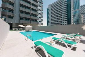uma piscina com cadeiras e cadeiras num edifício em Urban Caves - Stylish Condo Near Marina Walk With City Views em Dubai