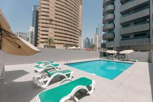 uma piscina com espreguiçadeiras e um hotel em Urban Caves - Stylish Condo Near Marina Walk With City Views em Dubai