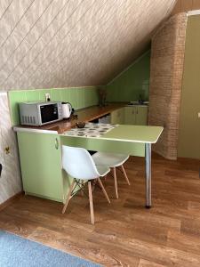 uma cozinha verde com uma mesa e um micro-ondas em Міні-готель em Kotowsk