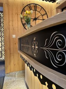 a wooden wall with a clock and a vase of flowers at Willa Siumno in Białka Tatrzanska