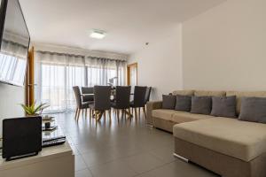 uma sala de estar com um sofá, uma mesa e cadeiras em Amazing Sea View Apartment Praia da Rocha em Portimão