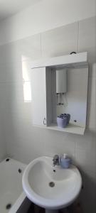 a white bathroom with a sink and a mirror at Apartman NM in Foča