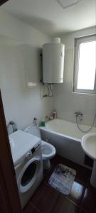 a white bathroom with a toilet and a sink at Apartman NM in Foča