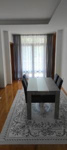 a dining room with a table and chairs on a rug at Apartman NM in Foča