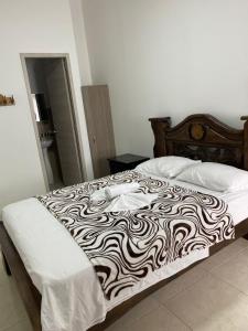 a bed with a black and white blanket on it at Hotel Monaco in Tuluá