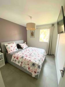 a bedroom with a bed with a floral bedspread and a window at Luxueux T3 Piscine et Vue Somptueuse in Sète +27 photos