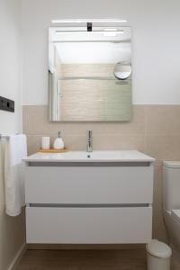 La salle de bains est pourvue d'un lavabo blanc et d'un miroir. dans l'établissement HOGAR DEL MAR, à Oia