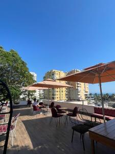 eine Terrasse mit Tischen, Stühlen und Sonnenschirmen in der Unterkunft Top view hostel in Durrës