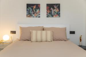 - une chambre avec un lit blanc et deux photos sur le mur dans l'établissement HOGAR DEL MAR, à Oia