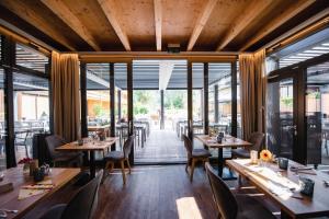 リエンツにあるDer Dolomitenhof - Tristachの木製のテーブルと椅子、大きな窓のあるレストランを併設しています。
