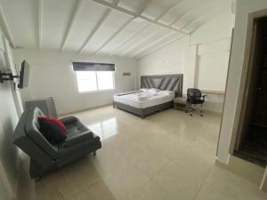 a bedroom with a bed and a couch and a chair at Hotel Monaco in Tuluá