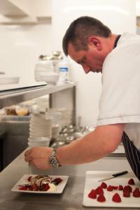 a man in a kitchen preparing a plate of food at Corr's Corner Hotel in Newtownabbey