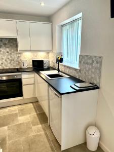a kitchen with white cabinets and a sink and a window at Pixie Cottage in Stoborough