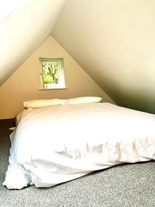 een slaapkamer met een wit bed op zolder bij Pixie Cottage in Stoborough