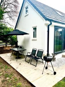 een patio met een grill en stoelen en een huis bij Pixie Cottage in Stoborough