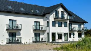 a white building with a black roof at Pokoje Gościnne in Łeba