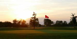 a golf course with a red flag on a green at Greenhouse-Sonnengolf in Zsira