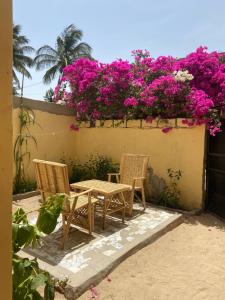 聖路易斯的住宿－Le Poulagou，庭院配有两把椅子和一张桌子,庭院里种着粉红色的鲜花
