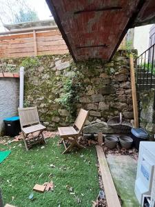 two chairs sitting in a yard with a stone wall at Studio centre village in Bocognano