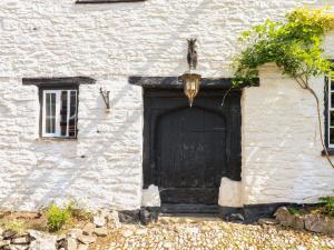 une porte noire sur le côté d'un bâtiment blanc dans l'établissement The Old Church House, à Newton Abbot