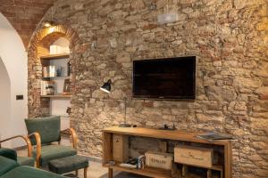 a living room with a stone wall with a television at Casa Masoni in Colle Val D'Elsa