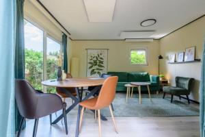 een woonkamer met een tafel, stoelen en een bank bij Gezellig ingericht vakantiehuis op de Veluwe in Putten