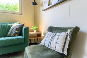 een woonkamer met een groene bank en een kussen bij Gezellig ingericht vakantiehuis op de Veluwe in Putten