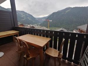 d'une table et de chaises en bois sur un balcon avec vue sur les montagnes. dans l'établissement Cœur de montagne, à Châtel