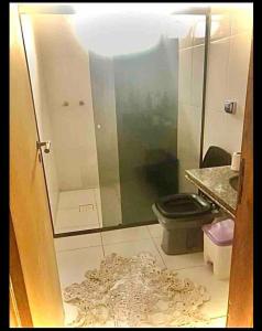 ein Badezimmer mit einem WC und einer Glastür in der Unterkunft Quarto confortável lago igapó in Londrina