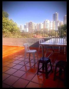einen Tisch und Stühle auf einer Terrasse mit Stadtblick in der Unterkunft Quarto confortável lago igapó in Londrina