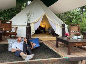 Ein Mann und eine Frau auf einem Bett vor einem Zelt in der Unterkunft Finca de la Vaca - Glamping & Camping in Mera