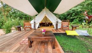Zelt mit einem Tisch und Stühlen auf einer Holzterrasse in der Unterkunft Finca de la Vaca - Glamping & Camping in Mera