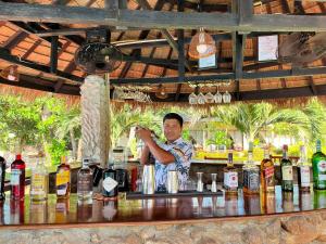 un homme derrière un bar avec des bouteilles d'alcool dans l'établissement The Waterfront Hotel at Fishermans Village, à Bophut 