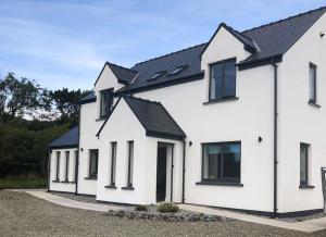 a row of white houses with black roofs at Bell View Holiday Home Sheeps Head in Bantry